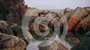 Natural rocky pool by sea, clear water forms tranquil oasis. Perfect for relaxation, nature scene inspires calm. Rocky