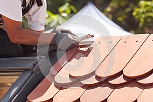 Natural roof tile instaalation. Roofer builder worker use ruller to measure the distance between the tiles.