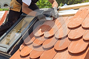 Natural roof tile instaalation. Roofer builder worker use ruller to measure the distance between the tiles. Roof with mansard wi