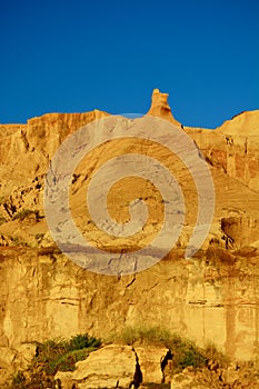 Natural sandstone formations: formed from cemented sand grains, yellow-orange in colour, forming rough cliffs against bright blue