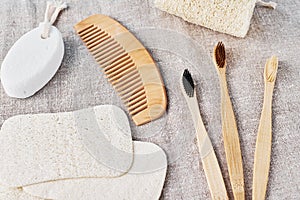 Natural set for bathing bamboo toothbrushes,  luffa spongle and wooden hairbrush on a linen background. Zero waste no plastic