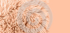 Natural sheepskin fur texture as background in trendy color 2024 year Peach Fuzz. Detail of sheep skin fur rug
