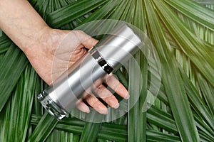Natural skincare beauty product concept, Cosmetic bottle containers in hand on green herbal leaves background. photo