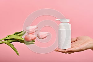 Natural skincare bottle, Hand showing cosmetic containers packaging with tulip flower essence extract