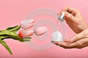 Natural skincare bottle, Hand showing dropping cosmetic containers packaging with tulip flower essence extract