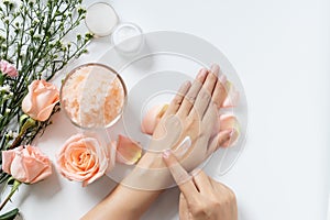 Natural skincare concept. woman apply white cream on her hands on white background with jar of cosmetic cream, salt spa scrub