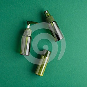 Natural skincare cosmetic bottles on green background. Bio beauty products packaging design. Flat lay, top view