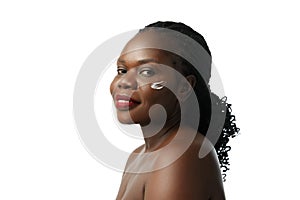 Natural skincare remedies. Beautiful African woman with face cream on cheeks posing isolated on white studio background