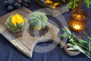 Natural small pumpkins, orange candles on white table, Halloween decorations