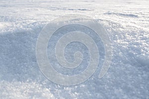 Natural snow texture of snowdrift. Winter backdrop with snowy ground. Patterns on snow surface.