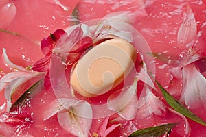 Natural soap bar in pink splashing water with flowers, body care concept,
