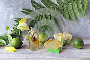 Natural soap, limes, aromatic oil for making a bath on a wooden table, spa, home cosmetics for body care