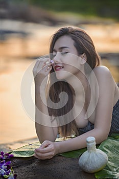 Natural Spa,Beautiful Woman relaxing in round outdoor bath with tropical flowers