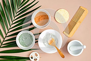 Natural SPA cosmetics for skincare, body and hair care. Top view facial clay masks, loofah, sponge, hair comb on peach background