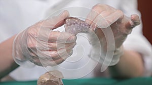 Natural stone amethyst or another mineral, stone. Wild amethyst in female hands in white gloves. Rock stone in hands