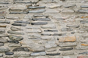 Close-up a concrete wall with the smooth sea boulders in it.