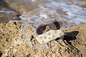 natural stone with funny and sad faces painted on it and sunglasses on the sea coast. Hello summer