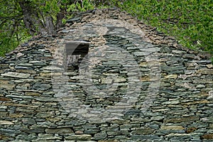 Natural stone wall of a morbid house in a garden