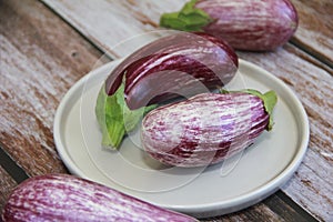 Natural striped eggplant fruits on a decorative plate
