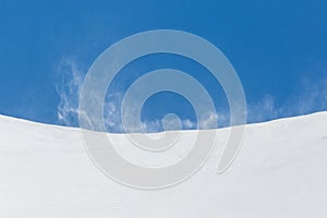Strong squall swirling snow in mountains, blue sky photo