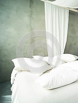 Natural style bedroom interior with a big bed, white linen and pillows. Concrete wall. Real photo of home design
