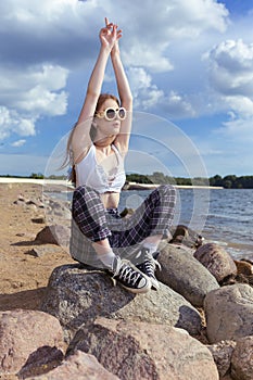 Natural Summer Portrait of Resting Relaxing Caucasian Blond Female Girl in Street Clothing Posing On Stones While Sitted On