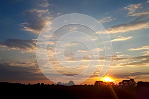 Natural sunset sunrise over field or meadow. Bright dramatic sky and dark ground. countryside landscape under scenic colorful sky