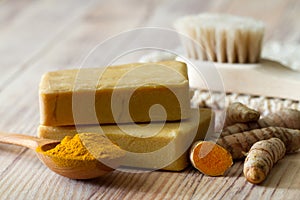 Natural turmeric soap, fresh and powdered turmeric root on wooden background, herbal skin care