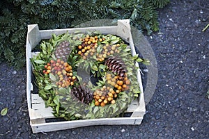 natural twig wreath is decorated with pine cones, red berries, gold shells and a raffia bow.