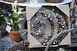 natural twig wreath is decorated with pine cones, red berries, gold shells and a raffia bow.