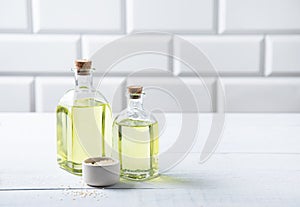 Natural vegetable oil from sesame seeds in a clear bottle on the white kitchen table. Dietary healthy food. Front view