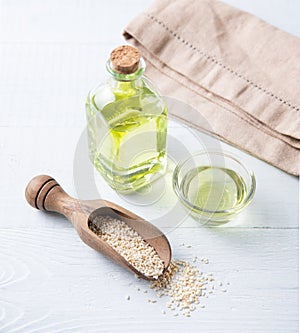 Natural vegetable oil from sesame seeds in a clear bottle on the wooden background. Dietary healthy food