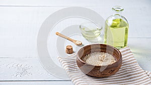 Natural vegetable oil from sesame seeds in a clear bottle on the wooden background. Dietary healthy food