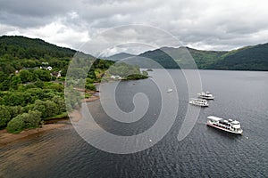 Natural view of tourist ferries on a calm sea and mountain landscape under a cloudy sky