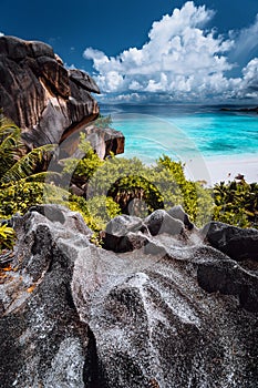 Natural viewpoint to beautiful impressive Grand Anse beach on La Digue island in Seychelles. Amazing white clouds above