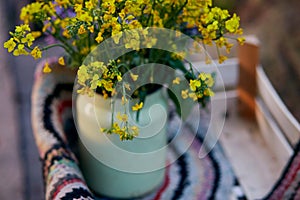 Natural vintage colorful handmade rug and spring flowers in watering can. Country life,cottage core, creative rustic