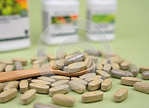 Natural vitamins and supplements in a wooden spoon on a green background. Healthy lifestyle concept. Close-up. Selective focus