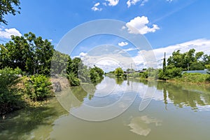 Natural water canal under a bright blue sky with white clouds