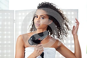 Natural is the way to go. an attractive young woman blowdrying her hair at home.