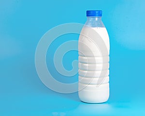 Natural white milk in plastic bottle on blue background with copyspace selective focus