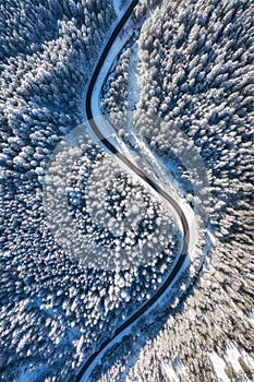 Natural winter landscape from air. Aerial view on the road and forest at the winter time. Winter chill. Forest and snow.