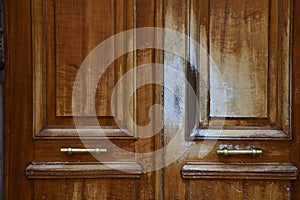 Natural wood textured double door panels with two old metal handles between wooden frames. Grunge details of Paris door.