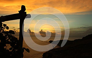 Beautiful evening sunset sky cloud over horizon, with wooden fence and land silhouette.