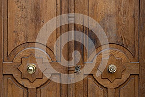 Natural wooden patterned door with two different round shiny vintage doorknobs in center of Jewish star shaped rosettes.