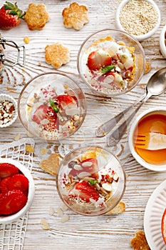 Natural yogurt with fresh fresh strawberries, granola, honey, nuts and seeds in a glass dishes. Delicious breakfast or dessert.