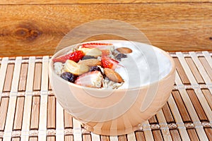 natural yogurt with homemade granola, strawberries and nuts in ceramic bowl on a table top view