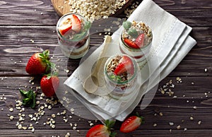 Natural yogurt with jam, muesli and fresh strawberry, mint leaves. Healthy breakfast concept.