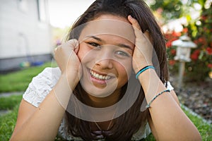 Naturally beautiful teenage girl lying on the grass with a happy smile.