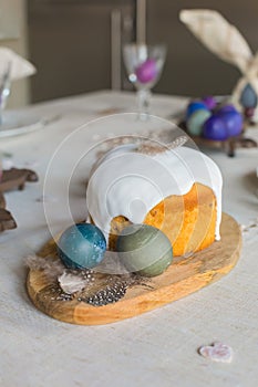 Naturally dyed Easter hen`s eggs, Easter cake, feathers, wooden hearts on linen background