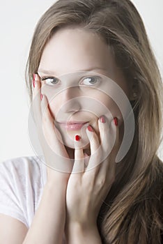 Naturaly beautiful woman touching her face with red nails hands